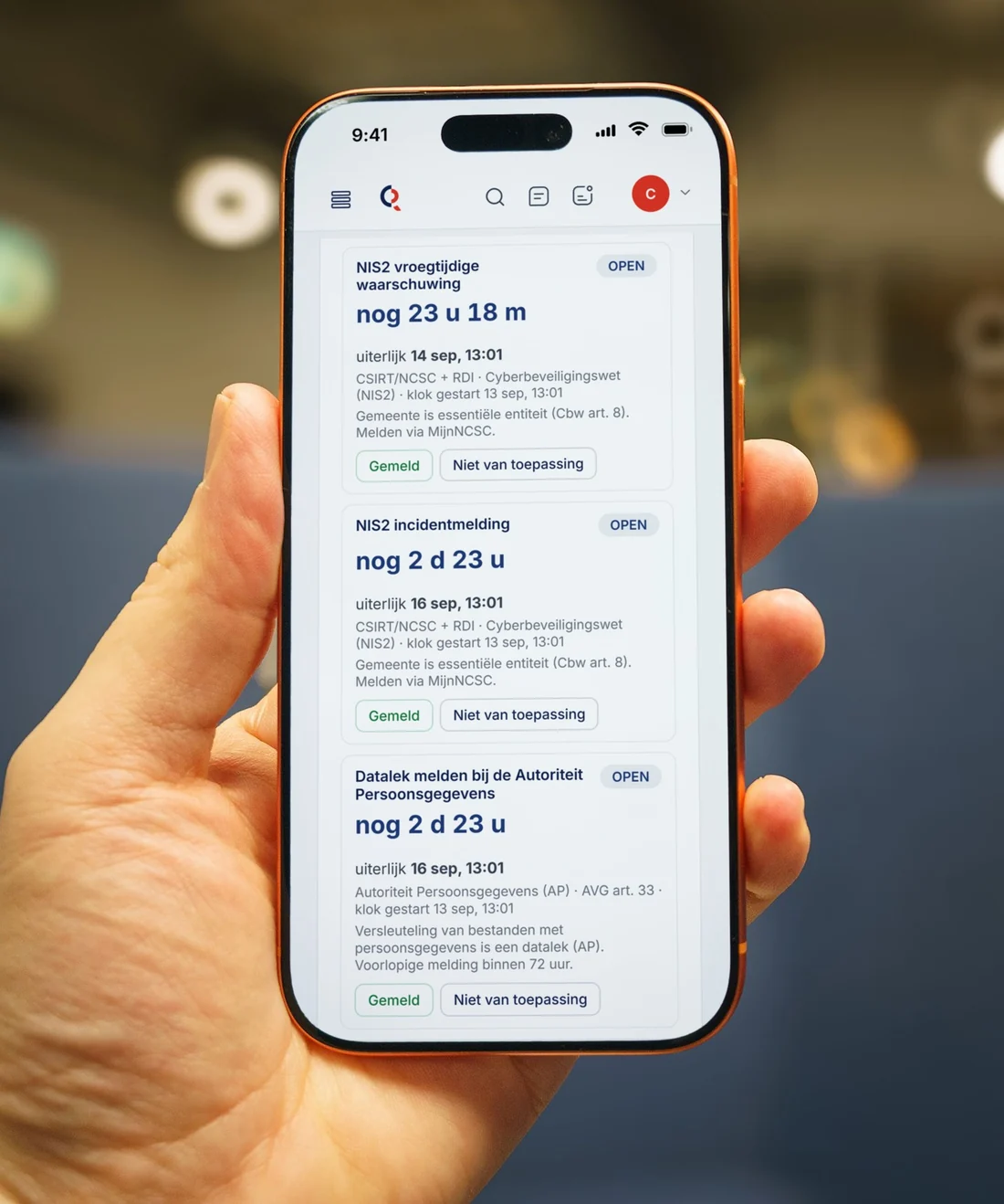 Iemand houdt een telefoon vast met de lopende meldklokken in CrisisRadar: nog 23 uur en 18 minuten voor de vroegtijdige waarschuwing aan het NCSC, en nog 2 dagen voor de melding bij de Autoriteit Persoonsgegevens.